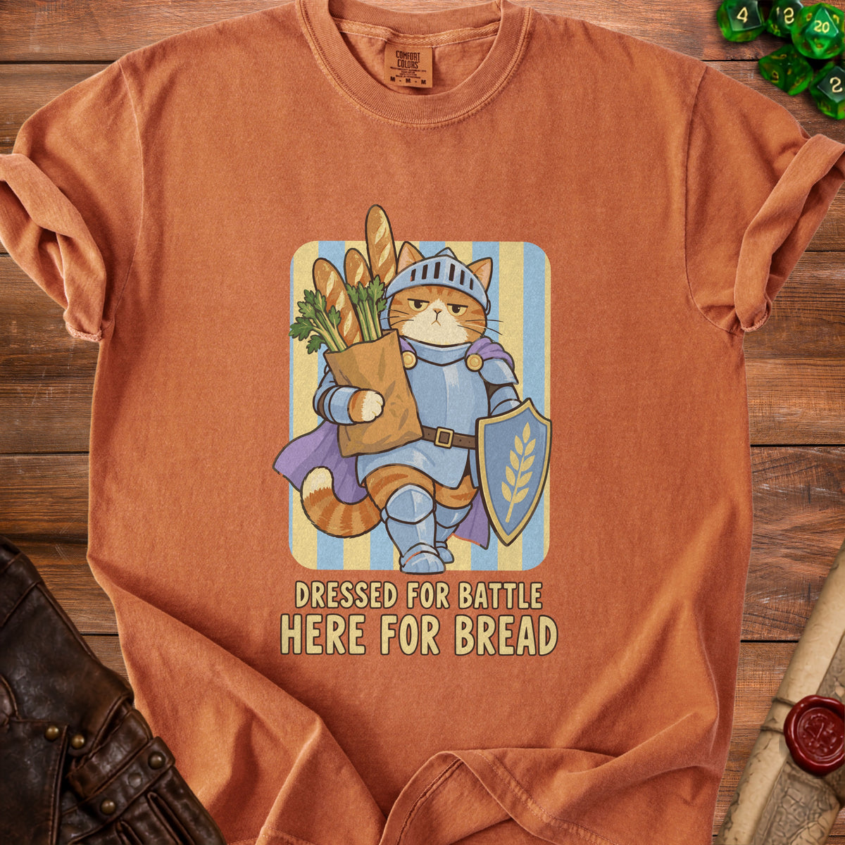Orange t-shirt with cartoon knight cat holding bag of bread, text "DRESSED FOR BATTLE HERE FOR BREAD".