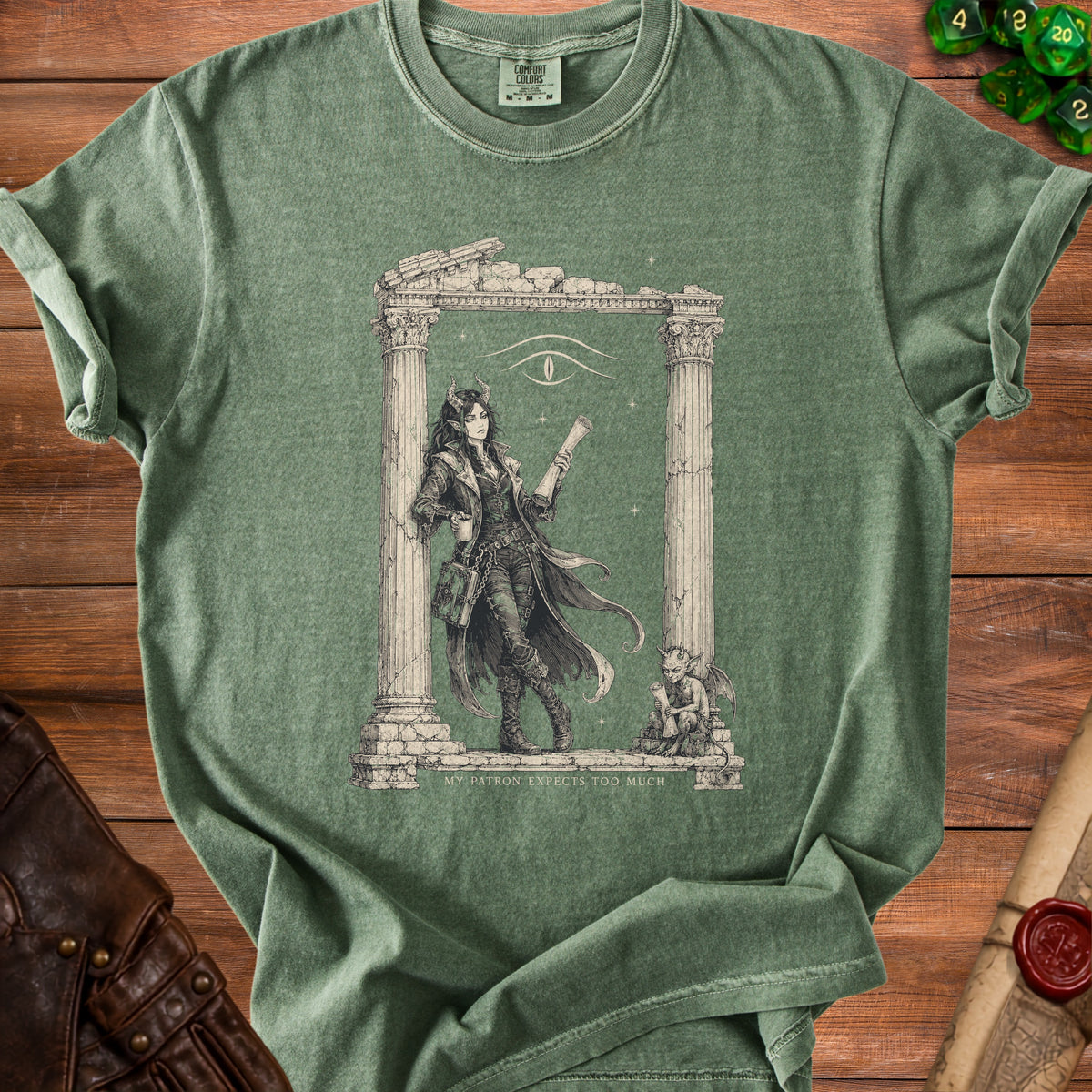 Green t-shirt with illustration of a devilish woman and text "MY PATRON EXPECTS TOO MUCH".