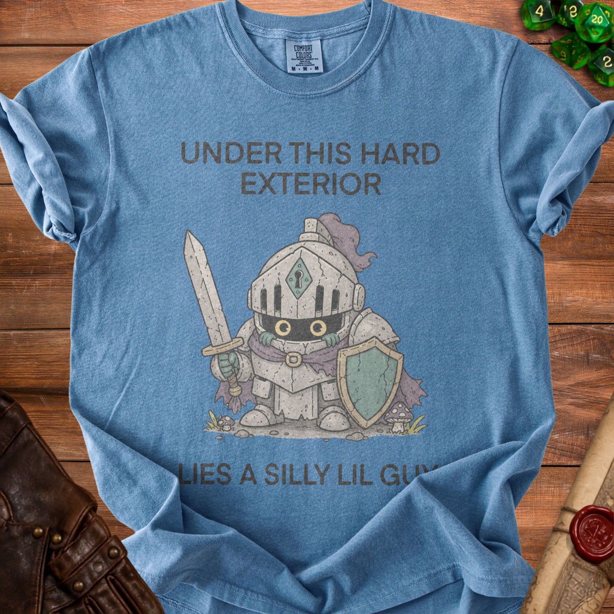 Blue t-shirt with cartoon knight graphic and text "Under this hard exterior lies a silly lil guy."