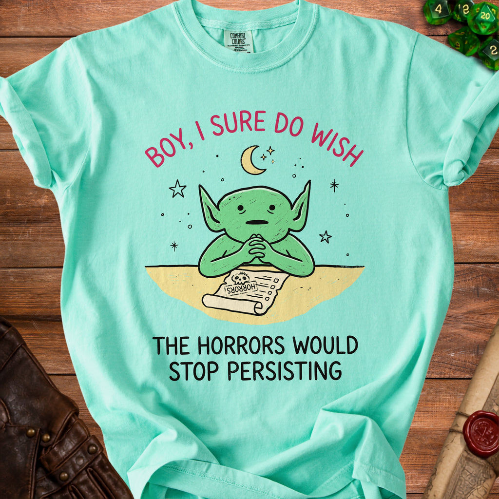 Mint green t-shirt with a green goblin reading a "Horrors" list with text "Boy, I sure do wish the horrors would stop persisting."