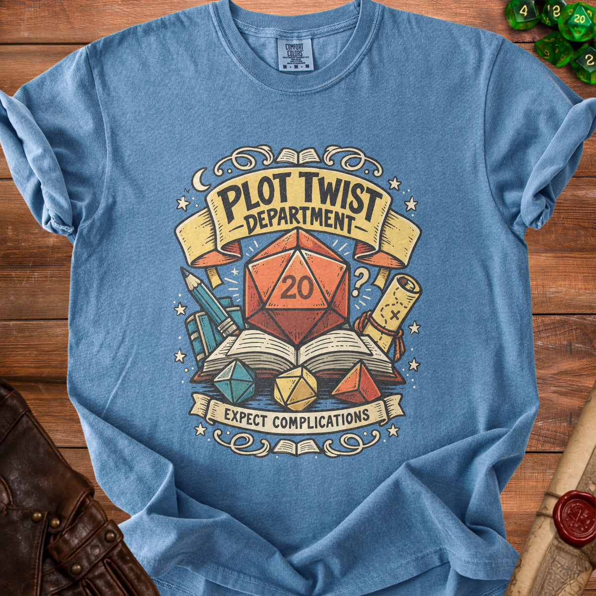 Blue t-shirt with "Plot Twist Department Expect Complications" and dice graphic.