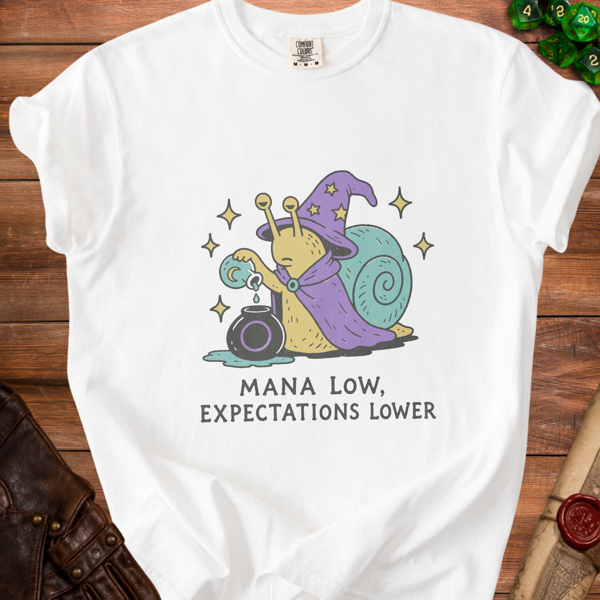 White t-shirt with a wizard snail pouring potion and text "MANA LOW, EXPECTATIONS LOWER".