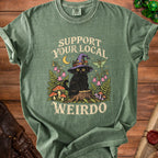 Green t-shirt featuring a graphic of a black cat in a witch hat with the text Support Your Local Weirdo.