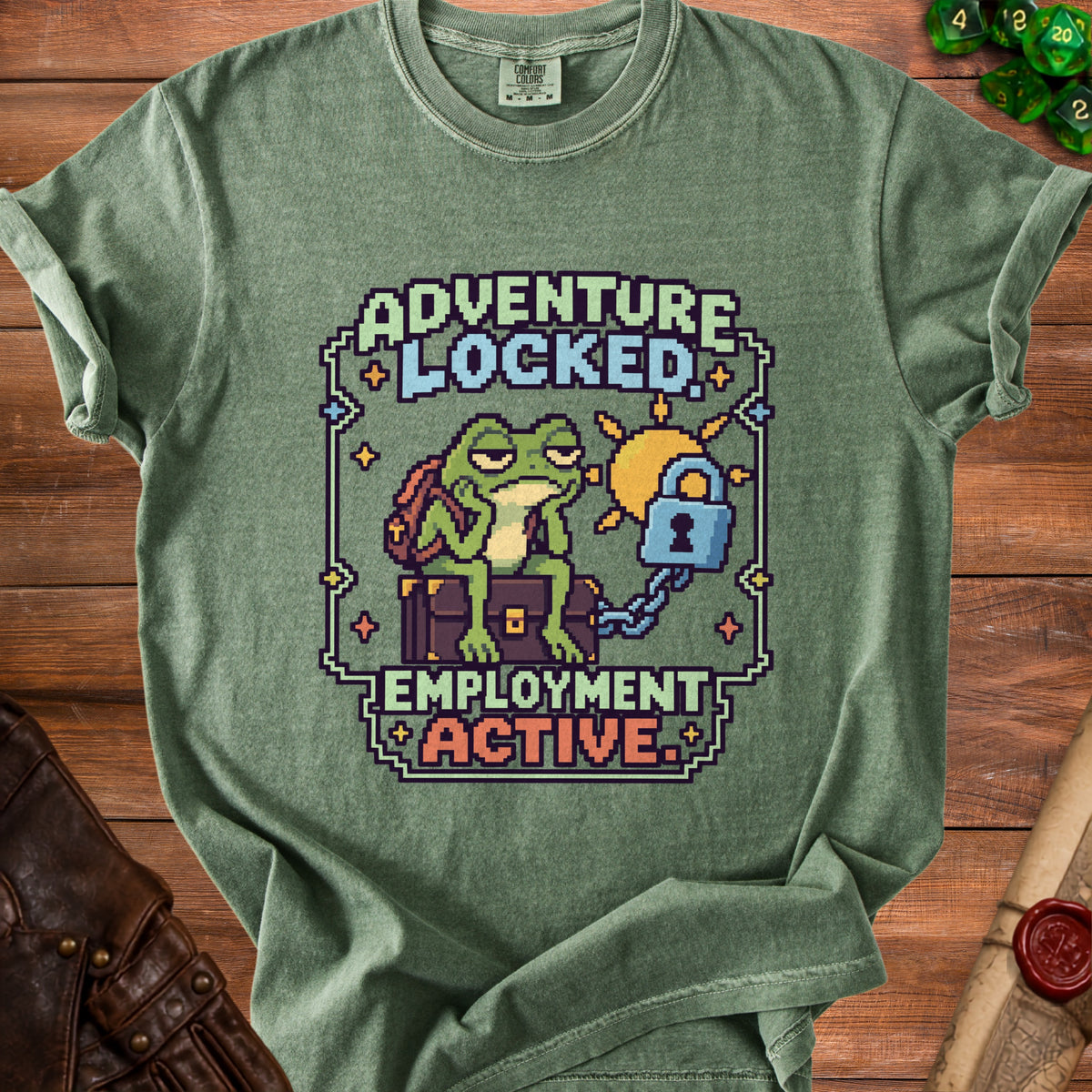 Green crewneck t-shirt featuring pixel art of a frog sitting on a trunk and the text ADVENTURE LOCKED EMPLOYMENT ACTIVE.