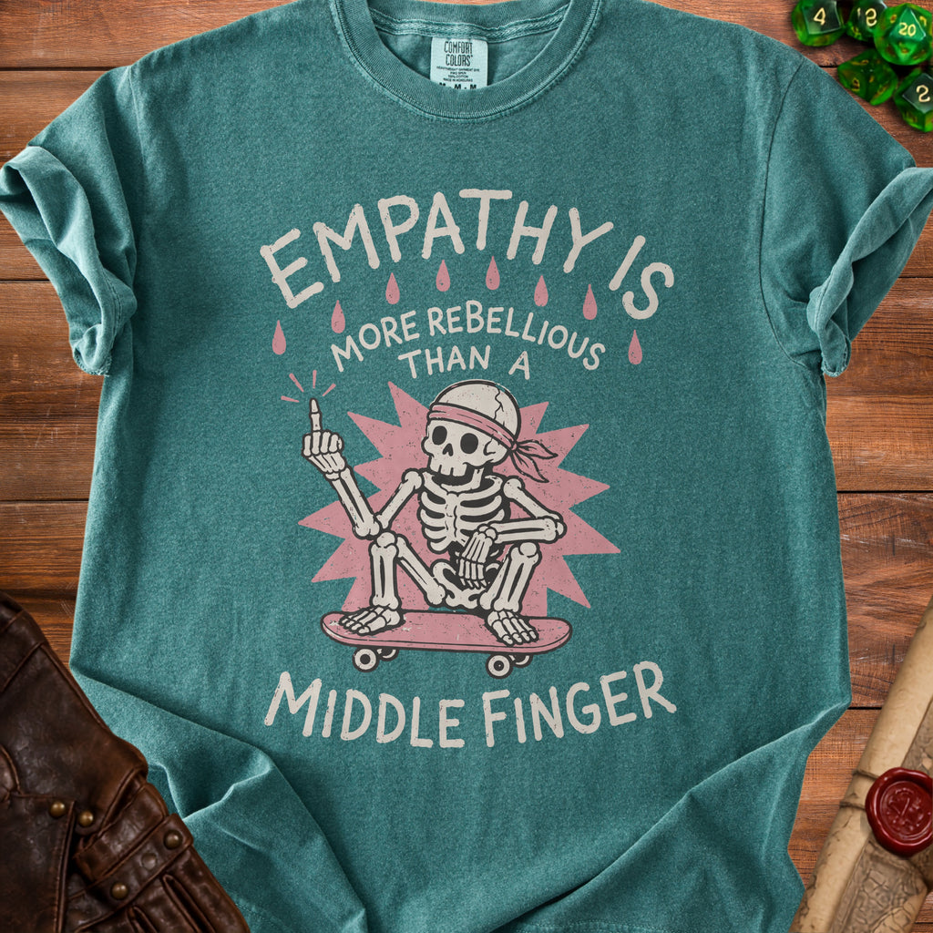Teal Comfort Colors t-shirt with skeleton on skateboard and text "EMPATHY IS MORE REBELLIOUS THAN A MIDDLE FINGER".