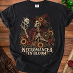 Skeleton necromancer with skull and book surrounded by flowers, text "Necromancer in Bloom".
