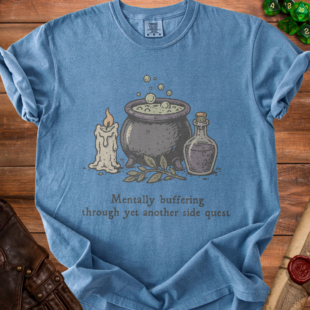 Blue t-shirt with cauldron, candle, bottle, and text "Mentally buffering through yet another side quest".
