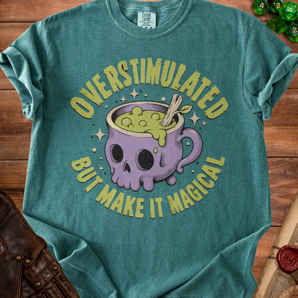 Green t-shirt with text "Overstimulated But Make It Magical" and a skull cauldron graphic.