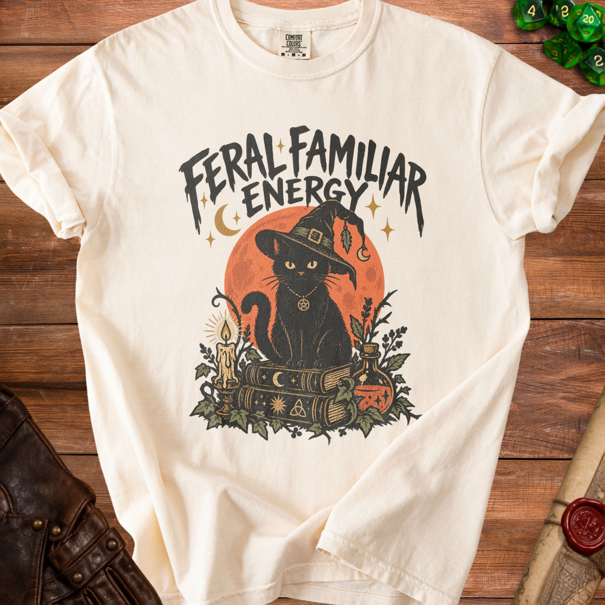 Cream t-shirt with black cat, witch hat, books, and "Feral Familiar Energy" text.