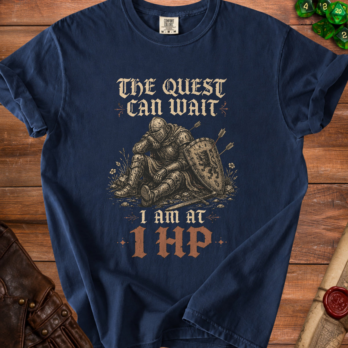 Navy t-shirt with knight graphic, "The Quest Can Wait" and "I Am At 1 HP" text.