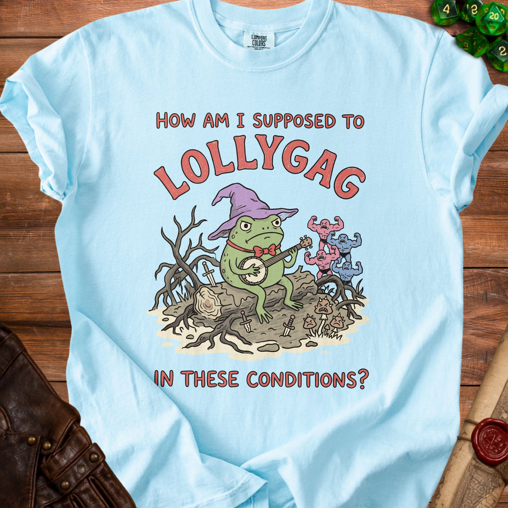 Light blue t-shirt with a frog wearing a wizard hat playing banjo, text "How am I supposed to lollygag in these conditions?".