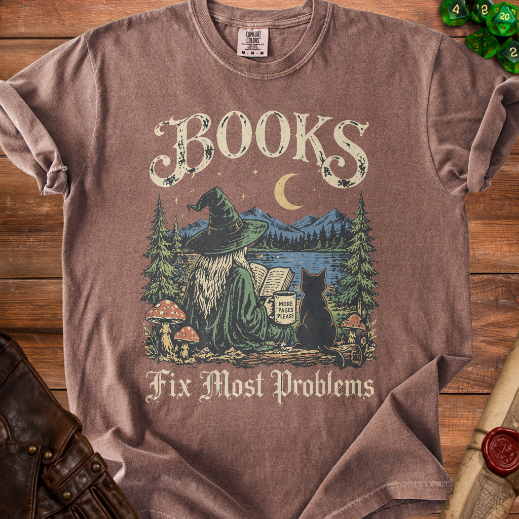 Brown t-shirt with graphic of a witch reading by a lake, text "BOOKS Fix Most Problems".