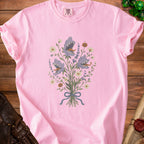 Pink t-shirt with a bouquet of purple monster flowers and a small pumpkin.