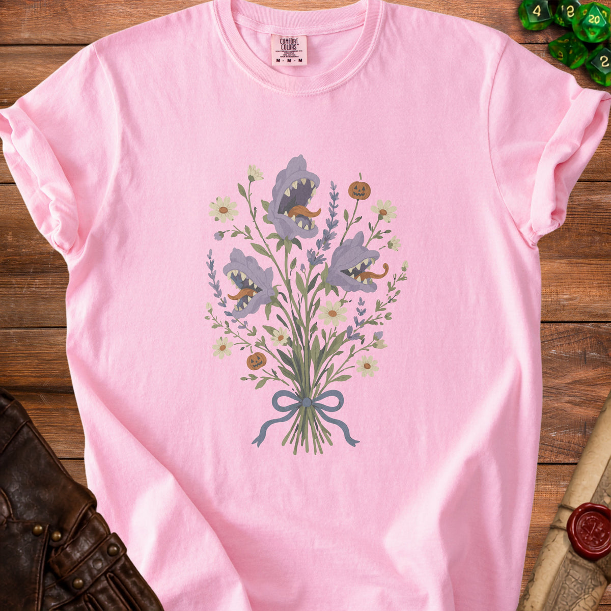 Pink t-shirt with a bouquet of purple monster flowers and a small pumpkin.