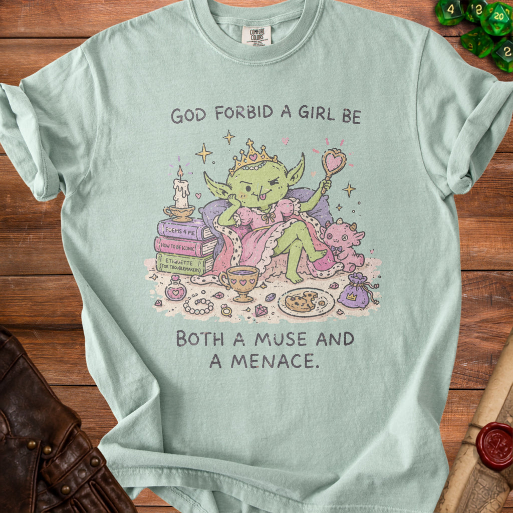 Light mint green t-shirt with "God forbid a girl be Both a muse and a menace" text and goblin illustration.