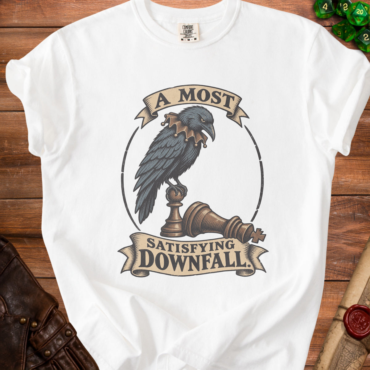 A white t-shirt featuring a vintage illustration of a raven perched on chess pieces, with text reading A Most Satisfying Downfall.