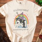 Cream t-shirt with illustration of a goblin wizard riding an orca over a rainbow.