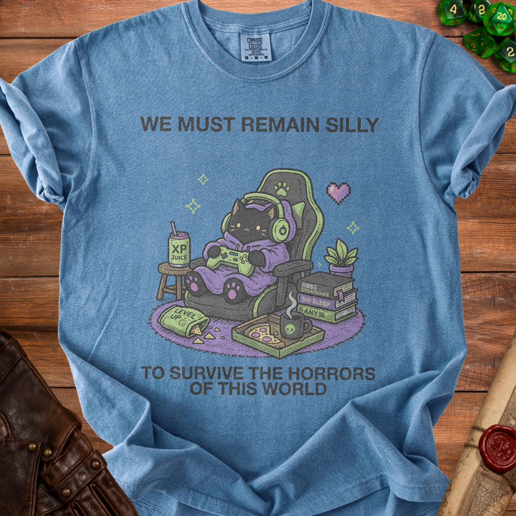 Blue t-shirt with a black cat gamer graphic and text "WE MUST REMAIN SILLY TO SURVIVE THE HORRORS OF THIS WORLD".
