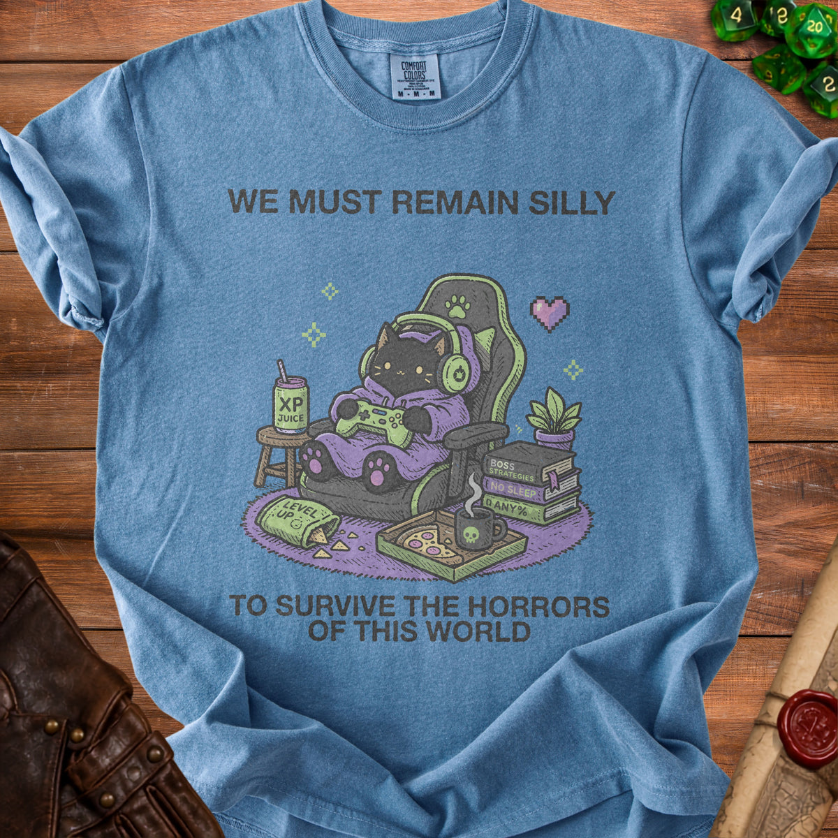 Blue t-shirt with a black cat gamer graphic and text "WE MUST REMAIN SILLY TO SURVIVE THE HORRORS OF THIS WORLD".