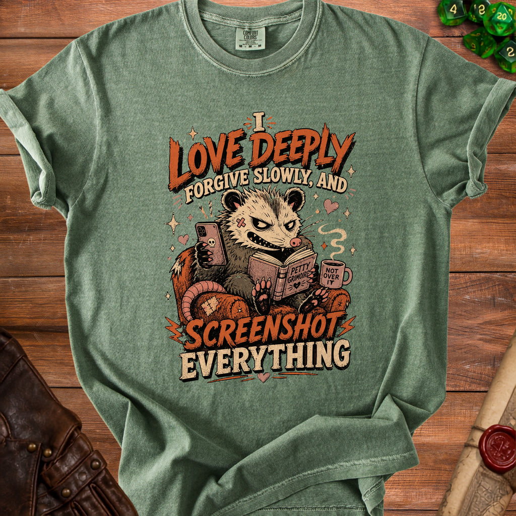 Green t-shirt with opossum graphic reading "I LOVE DEEPLY FORGIVE SLOWLY, AND SCREENSHOT EVERYTHING".