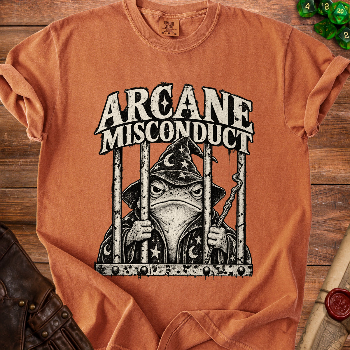 T-shirt with a wizard frog in jail design and "Arcane Misconduct" text.