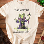 Cream t-shirt with a goat wizard graphic saying "This meeting could've been an em".