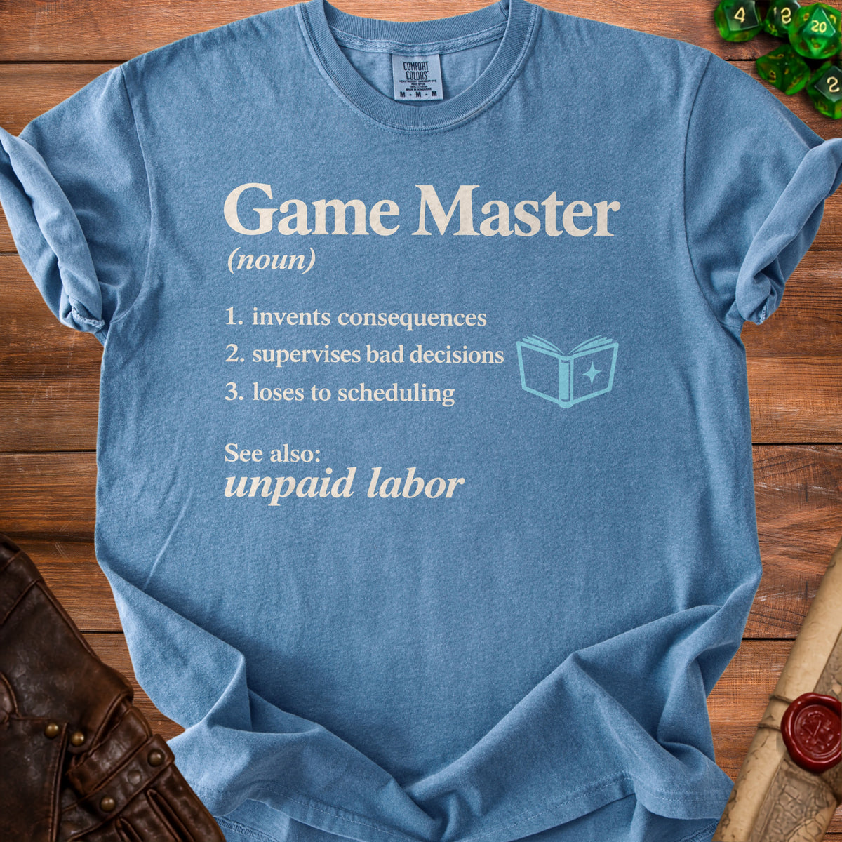Blue t-shirt with "Game Master (noun): invents consequences, supervises bad decisions, loses to scheduling. See also: unpaid labor."