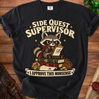 A black t-shirt featuring a cartoon raccoon sitting on books with a clipboard, twenty-sided die, and text reading Side Quest Supervisor.