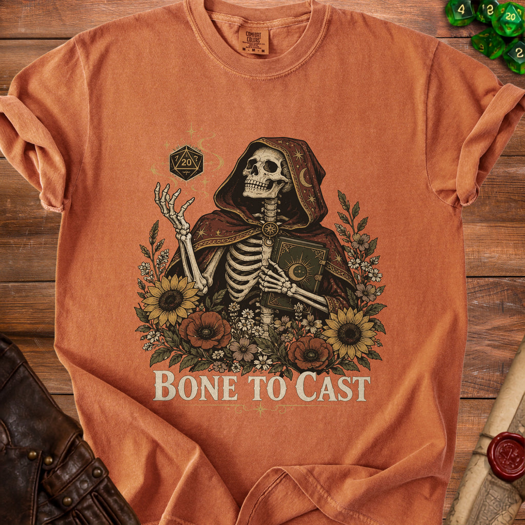 Skeleton wearing a hooded robe holding a book, surrounded by flowers and dice.