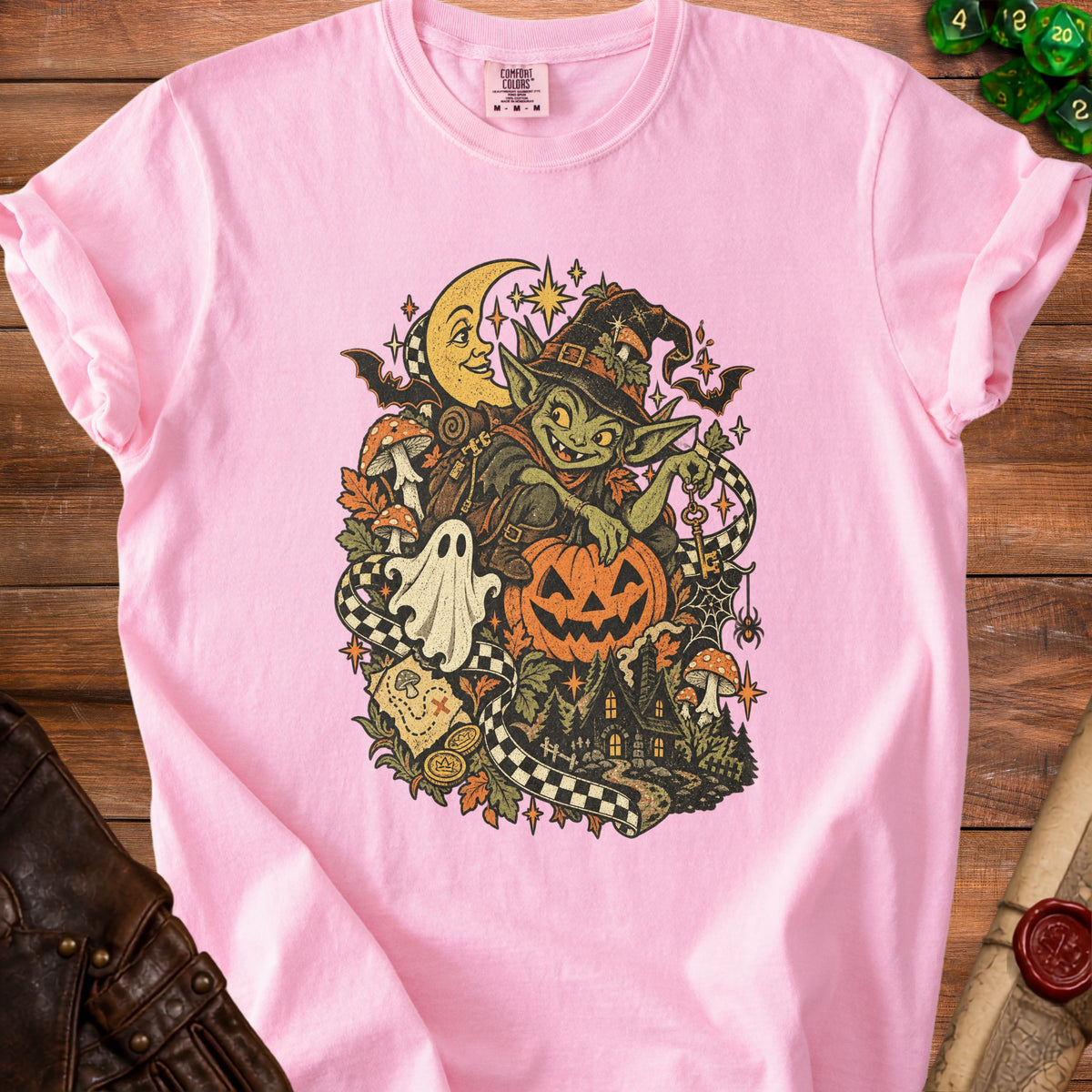 Pink t-shirt with Halloween goblin, pumpkin, ghost, moon, and haunted house graphic.