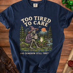 Navy t-shirt with skeleton, frog, mountains, and text "Too tired to care and somehow still thrive".