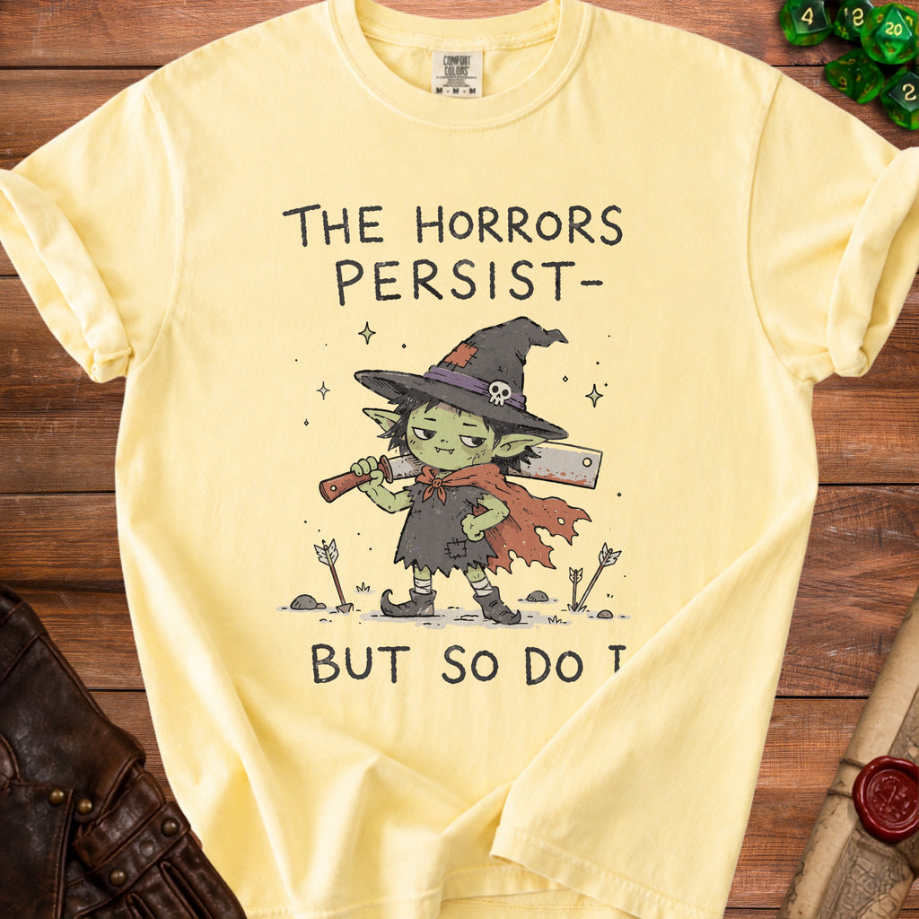 Yellow t-shirt with a goblin witch holding a cleaver and text "The Horrors Persist- But So Do T".