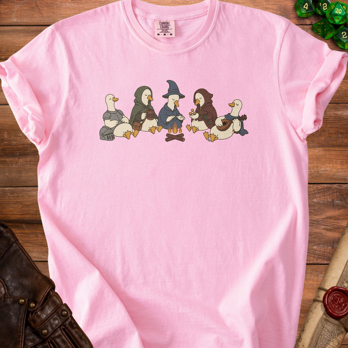 Pink t-shirt with five cartoon ducks dressed as fantasy characters by a campfire.
