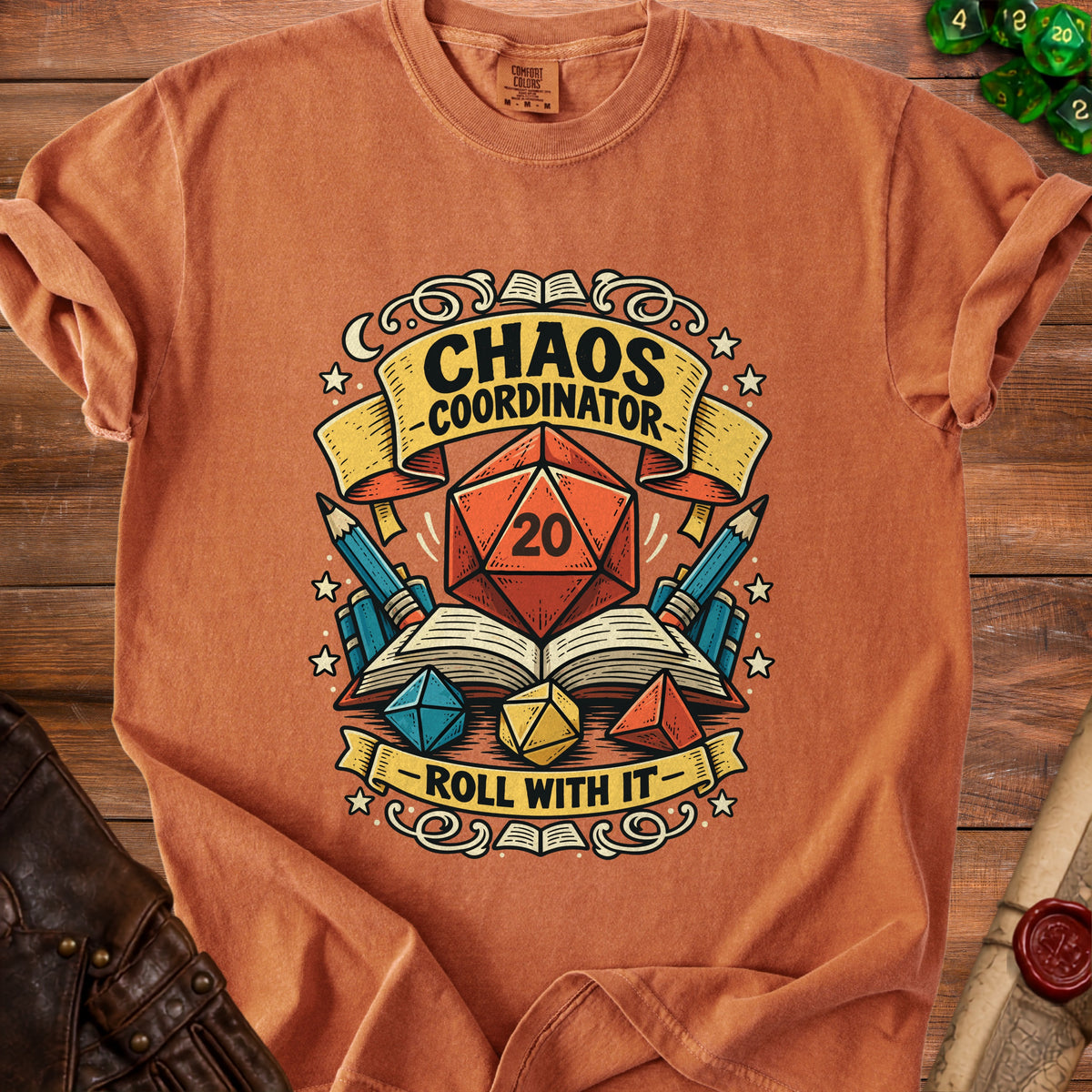 Orange t-shirt with "Chaos Coordinator" and "Roll With It" text, featuring dice and books.