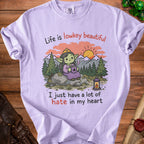 Lilac t-shirt with illustration of a crowned goblin holding coffee and text about hate.