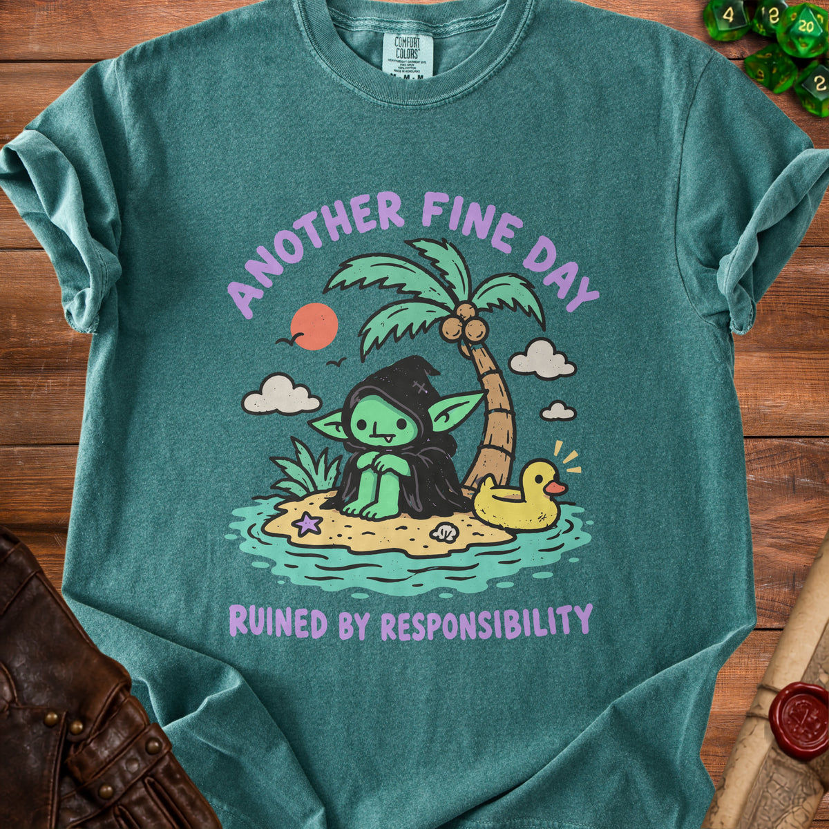 Teal t-shirt with graphic of a goblin on an island saying "Another Fine Day Ruined By Responsibility."