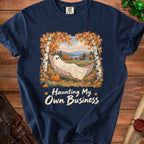 Ghost in hammock with text "Haunting My Own Business" on navy t-shirt.