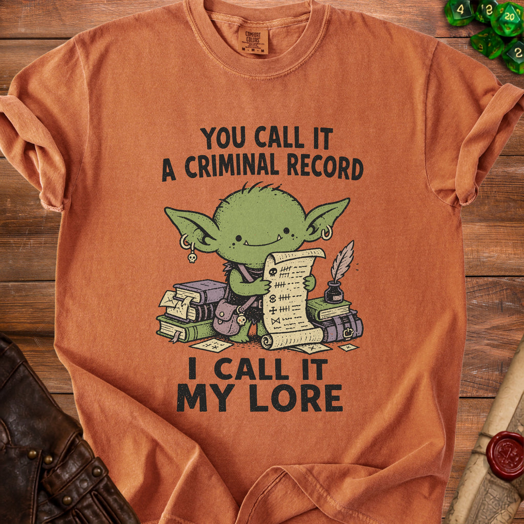 Orange t-shirt with a green goblin holding a scroll with tally marks and text.