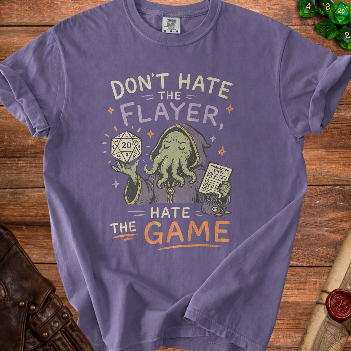 Purple t-shirt with a graphic of Cthulhu holding a d20 and character sheet, "Don't hate the flayer, hate the game."