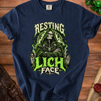Dark blue t-shirt featuring a green-toned graphic of a hooded skeleton with the text Resting Lich Face.