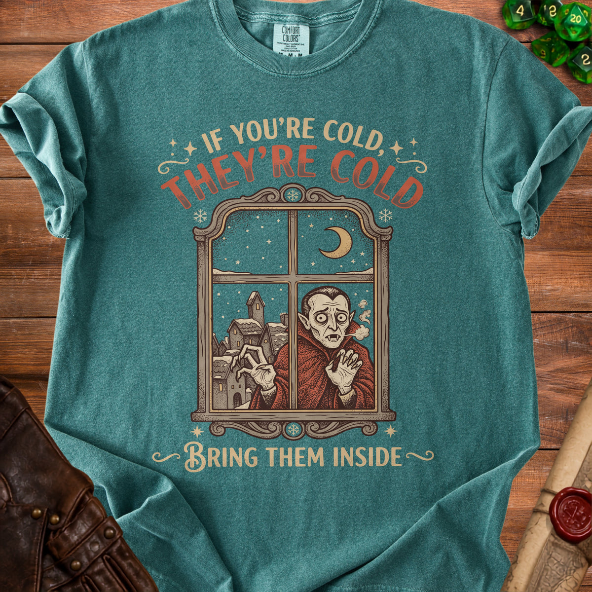 T-shirt with graphic of a vampire looking out a snowy window saying "If you're cold, they're cold, bring them inside."