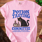 Pink t-shirt with "Potion Tasting Committee" design featuring a black cat and potion bottles.