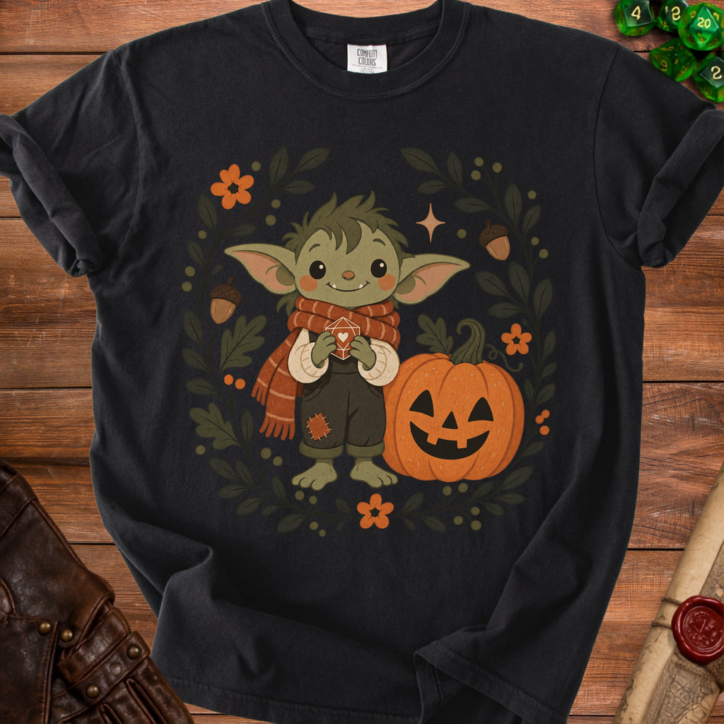 Black t-shirt with a cartoon green creature in a scarf and overalls holding a D20 die.