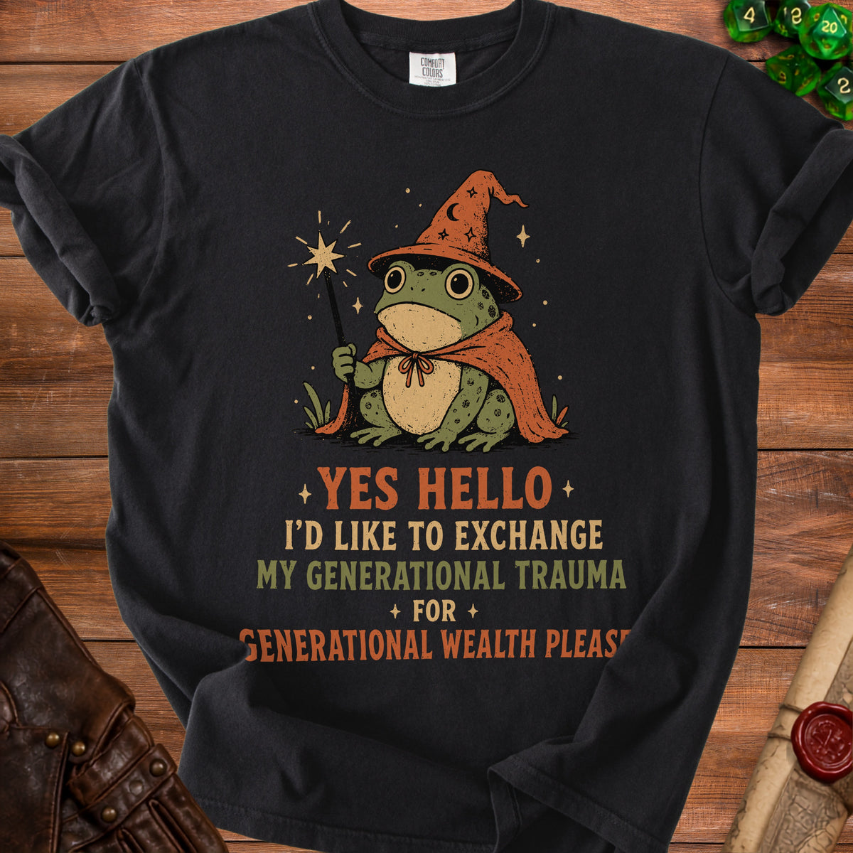 Black t-shirt with a wizard frog graphic and text saying "YES HELLO I'D LIKE TO EXCHANGE MY GENERATIONAL TRAUMA FOR GENERATIONAL WEALTH PLEASE".