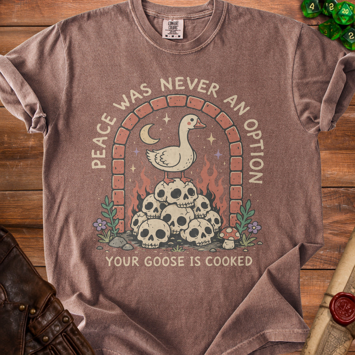 Brown t-shirt with a graphic of a goose on skulls under an archway with text.