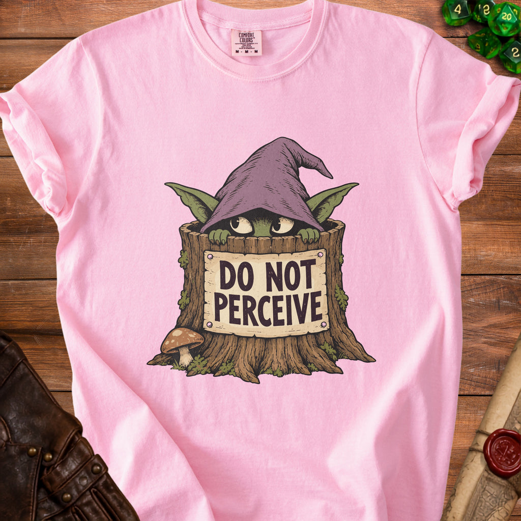 A pink t-shirt featuring a green goblin in a wizard hat hiding in a tree stump with text reading DO NOT PERCEIVE.