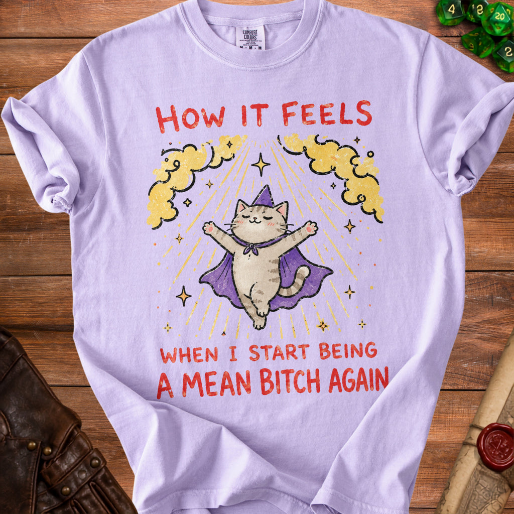 Lilac t-shirt with graphic of a cat in a cape and text "How it feels when I start being a mean bitch again."