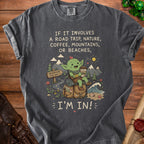 Green creature with coffee on backpack next to mountains, ocean, and road sign. "I'm In!"