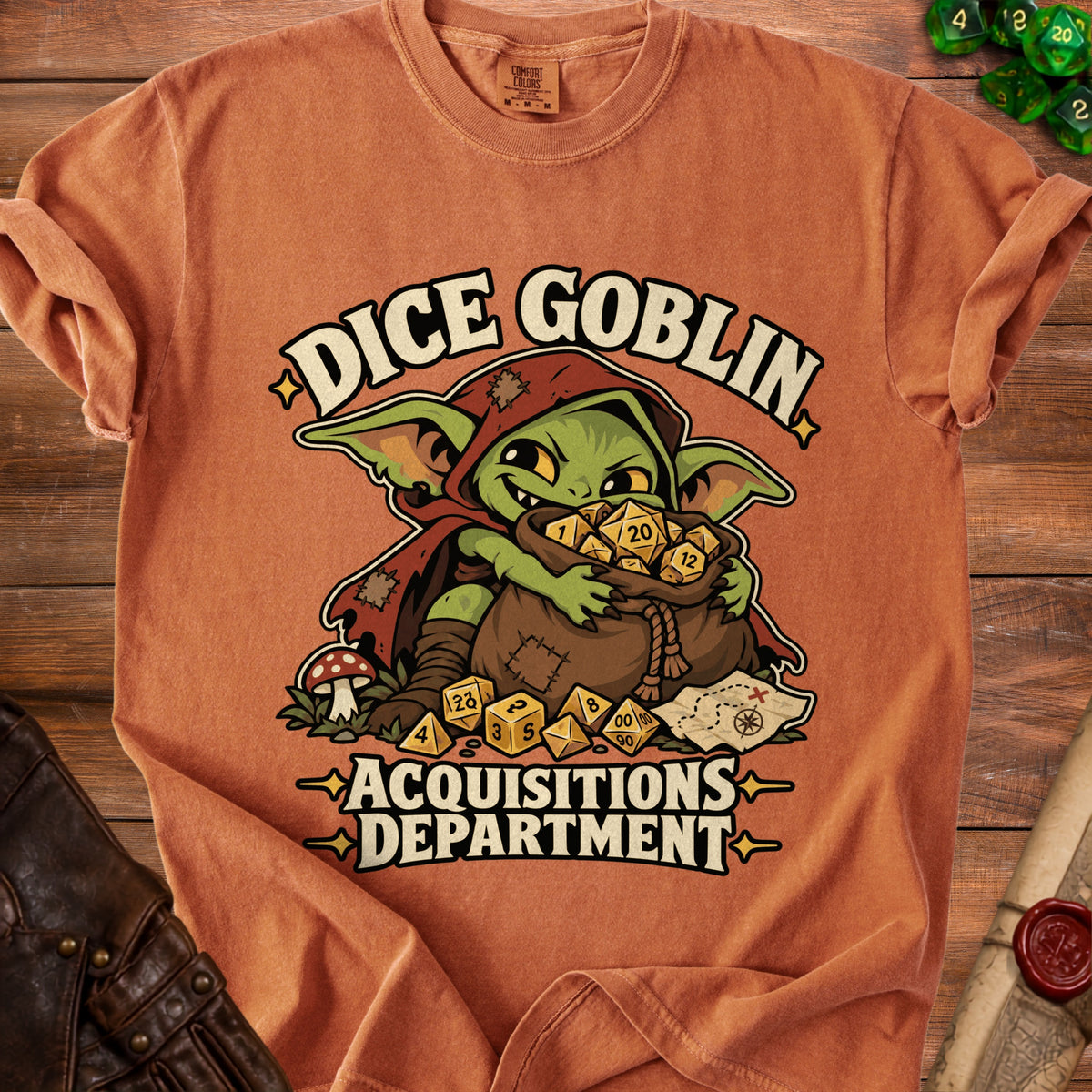An orange t-shirt featuring a goblin illustration and the text Dice Goblin Acquisitions Department.