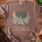 Brown t-shirt with a graphic of a sleeping cat, coffee, popcorn, and video game controller.